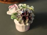 a small white vase with flowers in it on a table