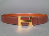 a close up of a brown belt with a gold h buckle