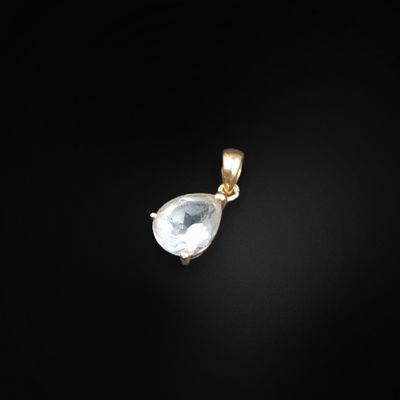 un pendentif en or orné d'une pierre blanche sur fond noir