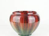 a red and green vase sitting on a white surface