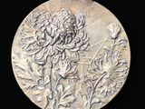 une assiette en argent avec l'image d'une fleur dessus
