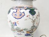 a white and blue vase with a gold base on a table