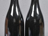 two bottles of red wine sitting next to each other on a table