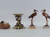trois statues d'oiseaux en bronze et un rocher posés sur une table