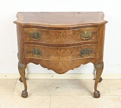 an old wooden chest of drawers with brass handles on a marble floor