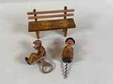 two figurines of people sitting on a bench