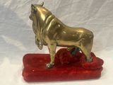 brass statue of a bull on a red cushion on a white background