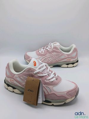 a pair of pink and white running shoes with a tag on them