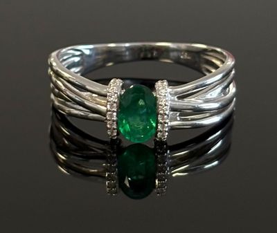 a close up of a ring with a green stone on a black surface