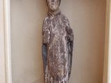 une statue représentant une personne assise sur une petite étagère