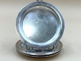 une assiette en argent posée sur un porte-assiette en argent, sur une table