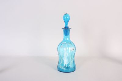 une bouteille en verre bleue munie d'une anse, posée sur une surface blanche