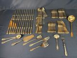 a lot of silverware on a table with a blue cloth