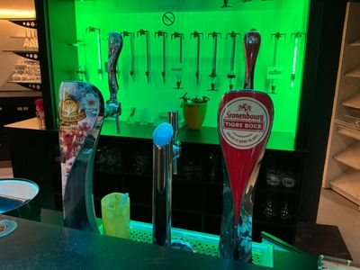 bottles of beer are lined up on a bar with a green light behind them