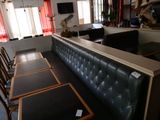 des tables et des chaises dans un restaurant, avec un bar en arrière-plan