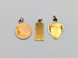 three gold pendants with a heart and a cross on them
