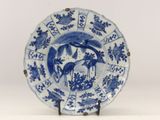 a blue and white plate with a bird and flowers on it