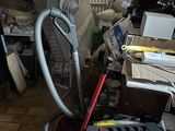une photo d'une pièce en désordre avec un aspirateur et d'autres objets éparpillés