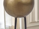 a gold vase sitting on a wooden table in front of a window