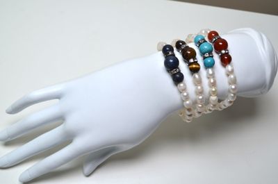 une main de mannequin blanche tenant un bracelet orné de perles multicolores