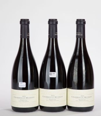 trois bouteilles de vin sont alignées sur une surface blanche