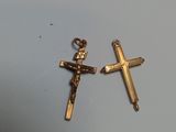 deux croix en or, chacune ornée d'une croix, posées sur une table