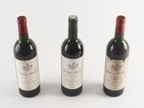 three bottles of wine sitting next to each other on a white surface