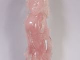 une statue rose posée sur une surface blanche
