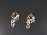 une paire de boucles d'oreilles en or et diamants sur une surface noire