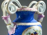 a blue vase with a handle that has flowers on it