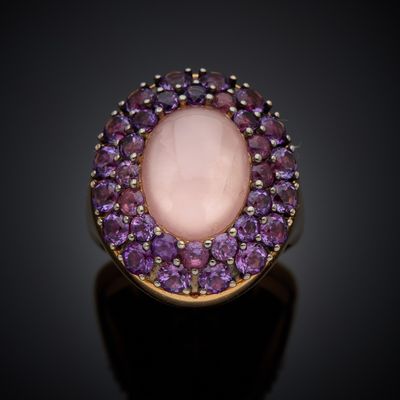 a close up of a ring with a pink stone surrounded by purple stones