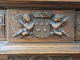 a wooden cabinet with carvings of angels and a coat of arms
