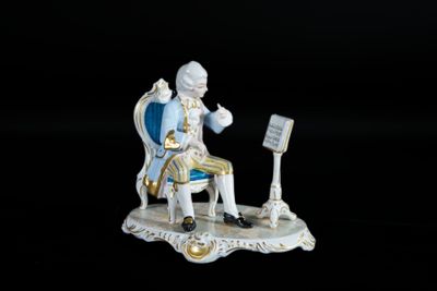 une figurine représentant un homme assis sur une chaise