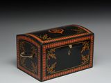 une petite boîte noire et rouge ornée de motifs dorés