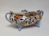a close up of a bowl with flowers on it on a white surface
