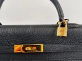a black leather handbag with a gold lock on the handle