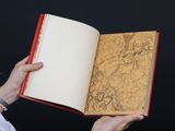 a woman holding an open book with a drawing on it