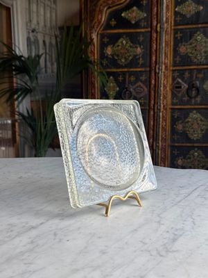 a glass plate sitting on a marble table with a gold stand