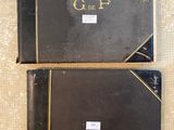 two black books with gold trims are sitting on a table