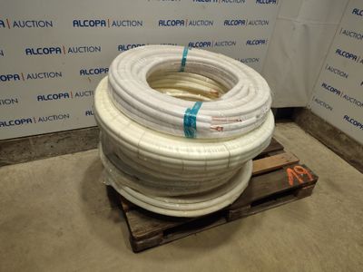 une pile de tuyaux blancs posée sur une palette devant un mur