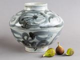 un vase bleu et blanc, avec une figurine à côté