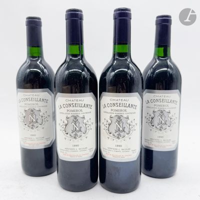 quatre bouteilles de vin sont alignées sur une surface blanche