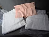 a pile of folded white and pink shirts on a black couch