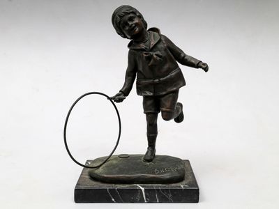 statue en bronze représentant un garçon tenant une raquette de tennis, posée sur un socle en marbre