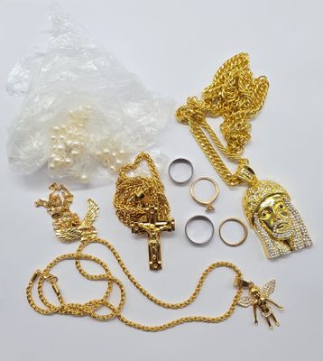 plusieurs chaînes en or, des bagues, des bagues et d'autres bijoux posés sur une surface blanche