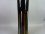 un vase noir et or posé sur une surface blanche
