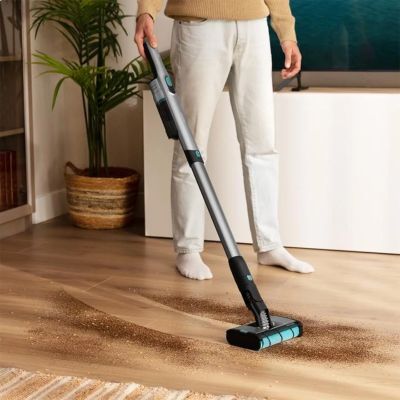 man using a vacuum to clean a hardwood floor in a living room