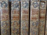 several old books are lined up on a shelf in a library