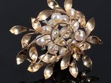 a close up of a pearl and gold broochle on a black surface