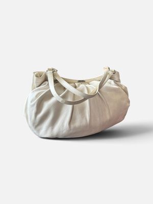 Le grand sac blanc est posé par terre, près d'un mur blanc.